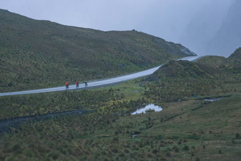 a long winding road on a hillside with people walking along it