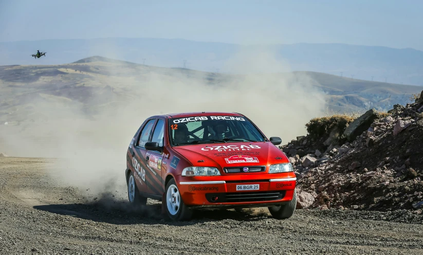 a red car driving on a dirt road