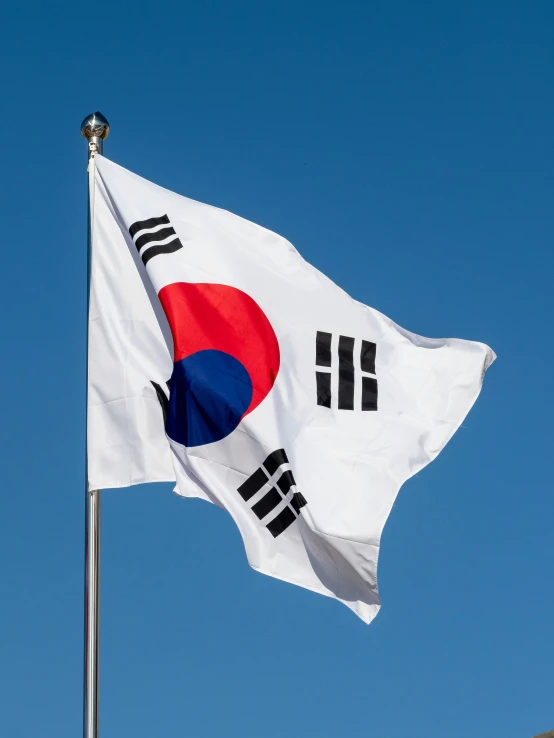 a white korean flag flying against the blue sky