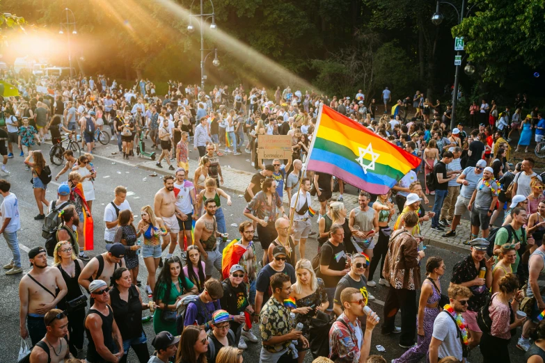 large group of people walking through the street with a rainbow flag