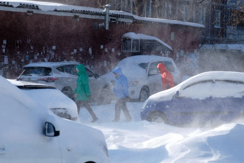 several people walking through the snow next to cars