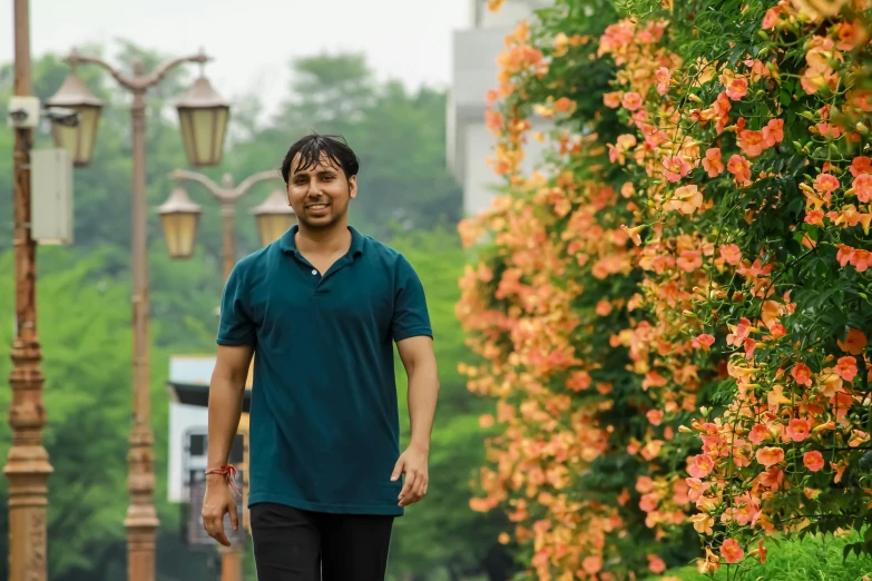 man walking on sidewalk next to flowers and lampposts