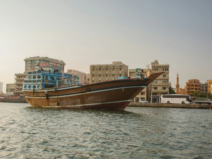 large wooden boat in a body of water near a city