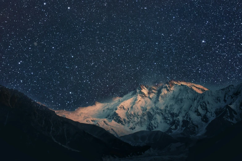 the night sky in front of a snow covered mountain