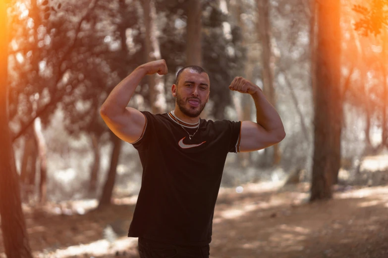 a man standing in the woods flexing his muscles