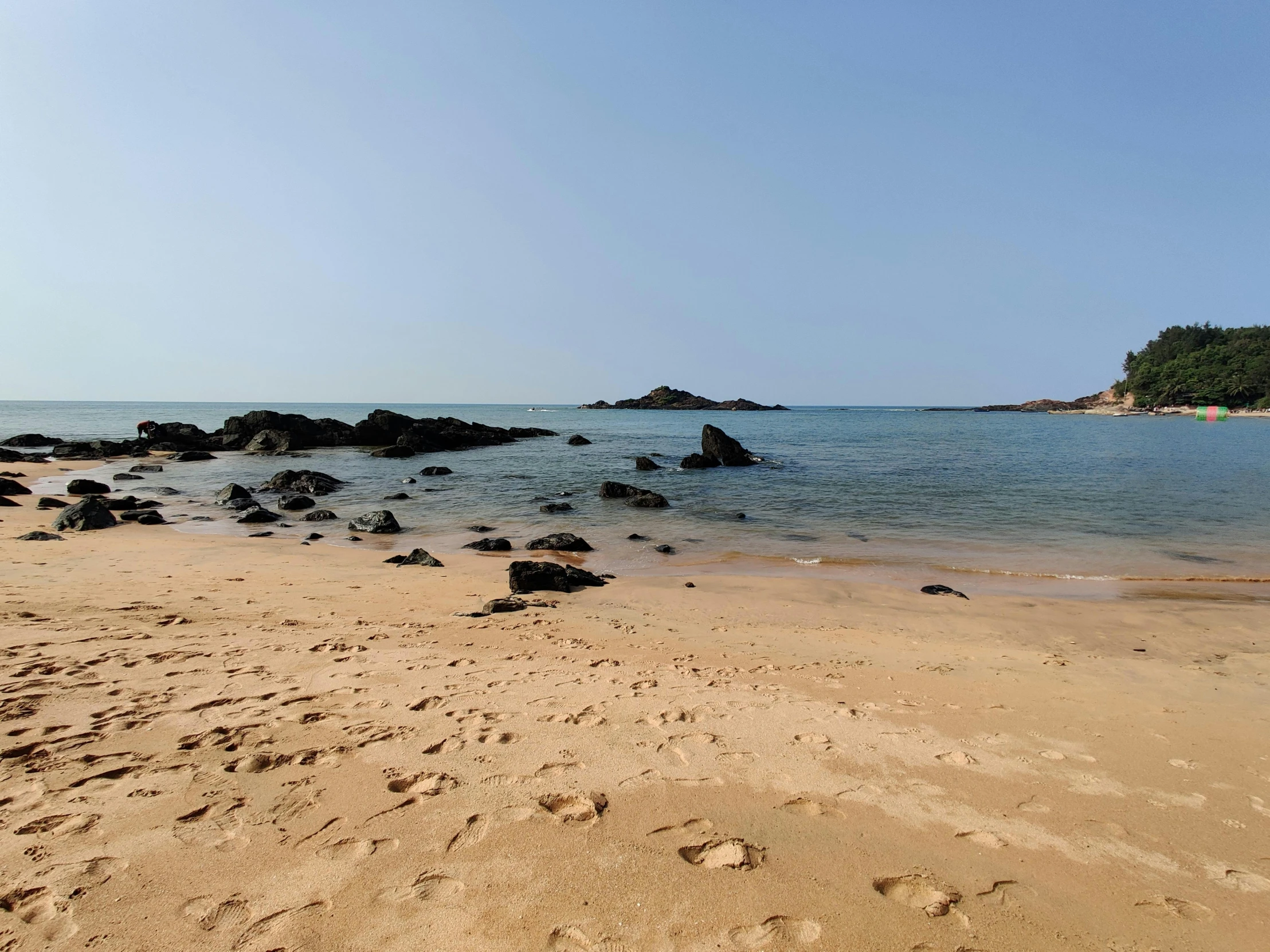 sand, rocks and seaweed are on the shore near the ocean