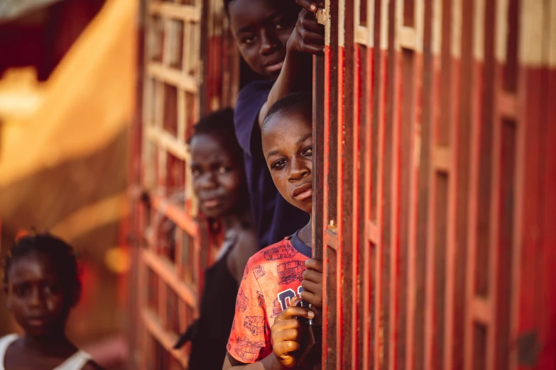 young children hanging on to bars outside a door