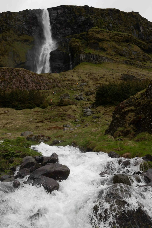 a water fall falls over rocks on a hill side