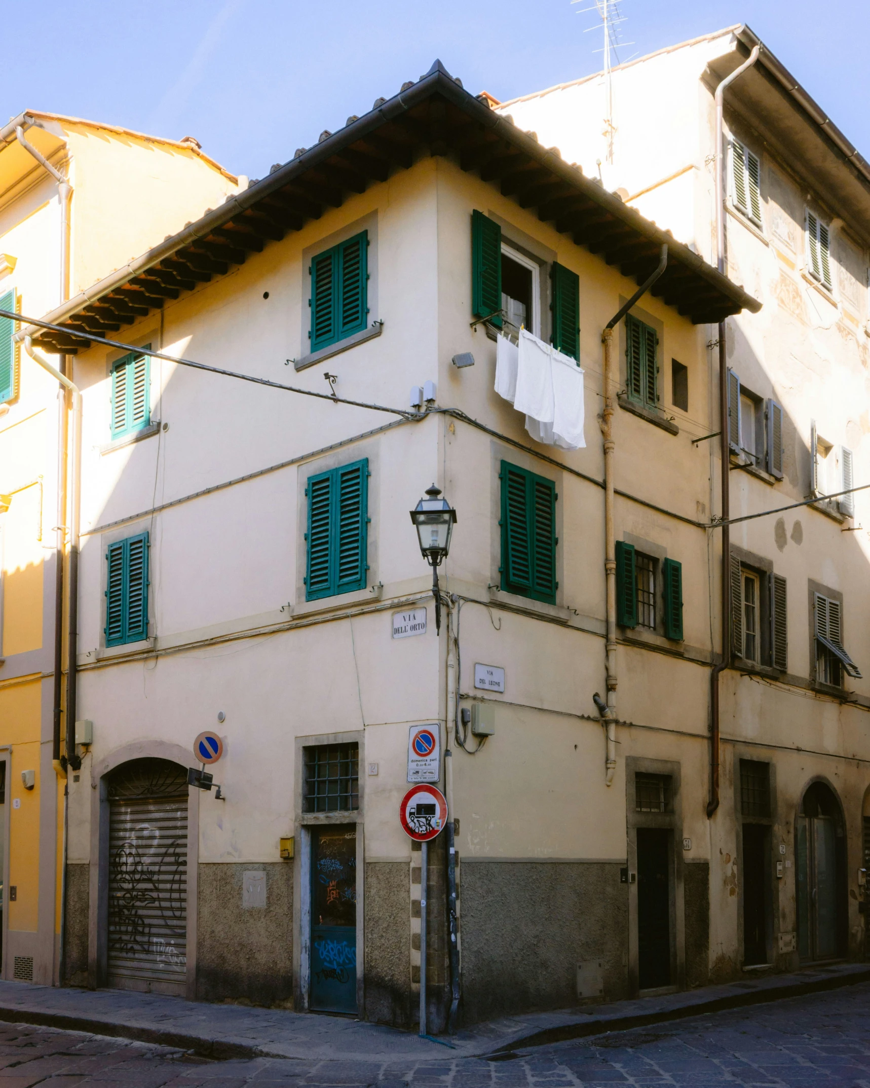 an old building with green shutters on a street corner