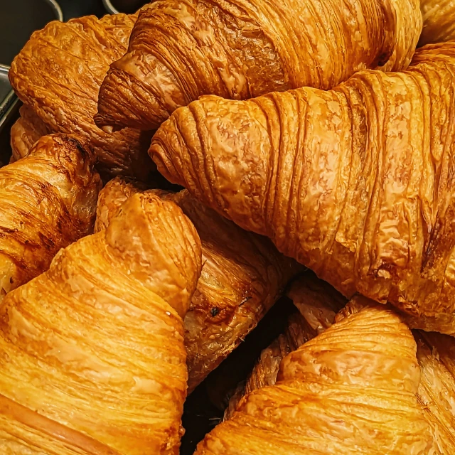two bunches of large golden croissants are in front of some smaller ones