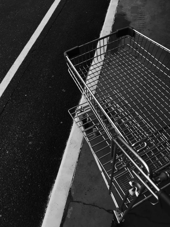 black and white image of a shopping cart by the side of the road