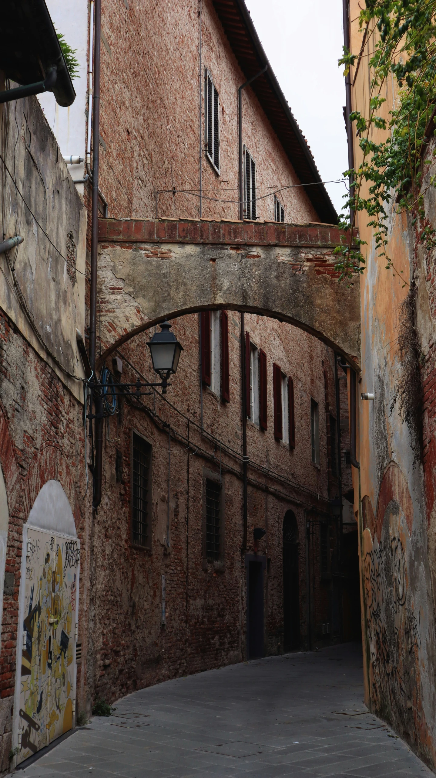 an old alley with brick walls and a bridge above