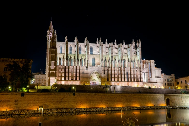 cathedral lit up at night with reflecting in water