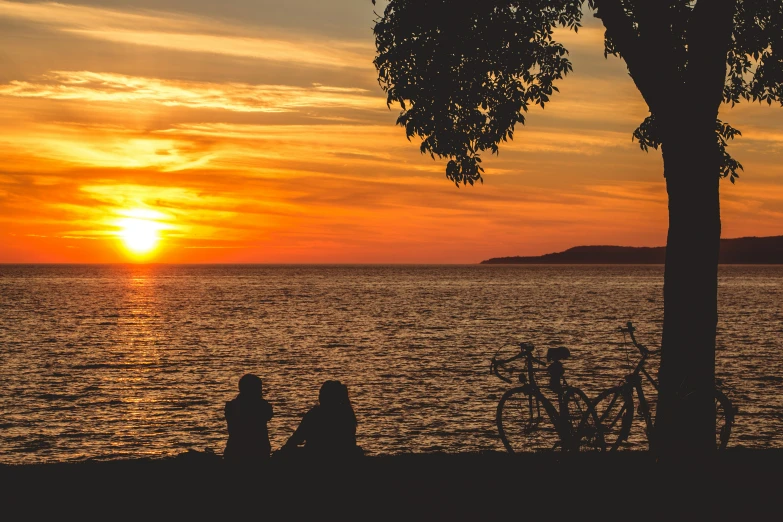 two people sitting at the edge of a bench on the shore