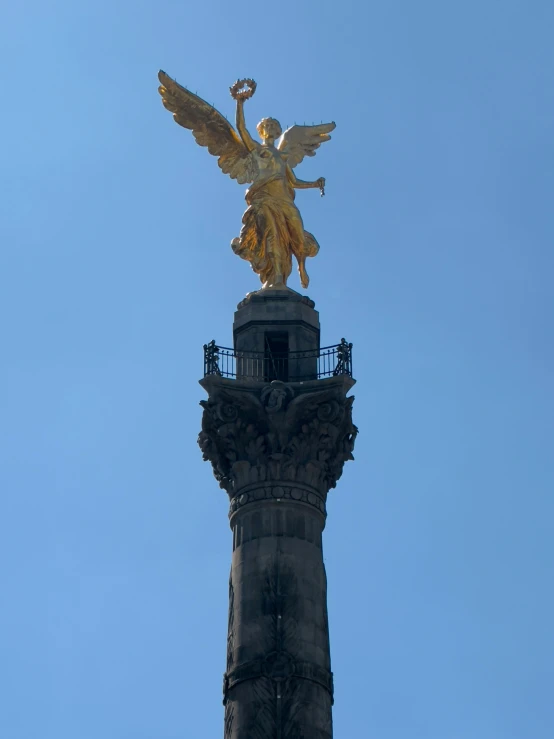 the angel is perched high on the building