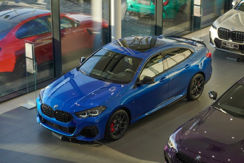 a blue bmw car driving through a building with multiple other cars