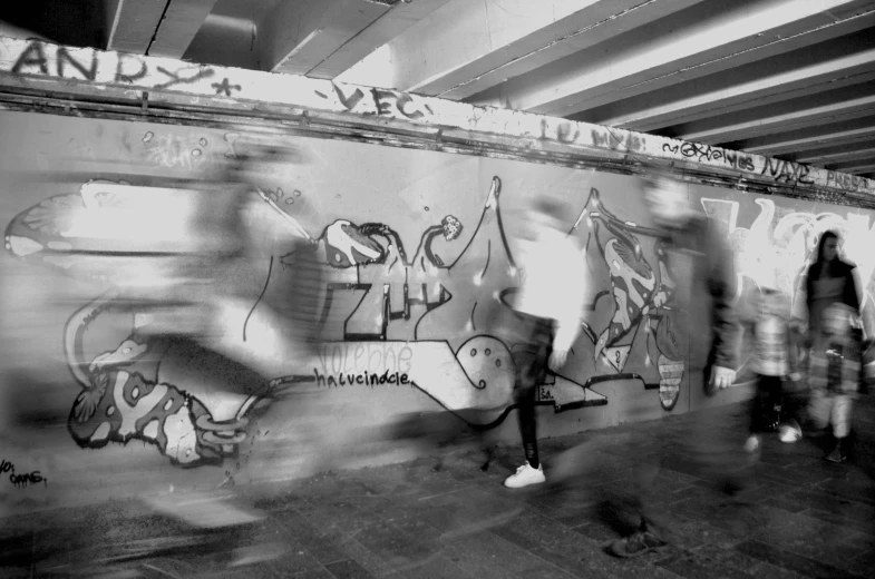 some people standing in front of a wall covered in graffiti