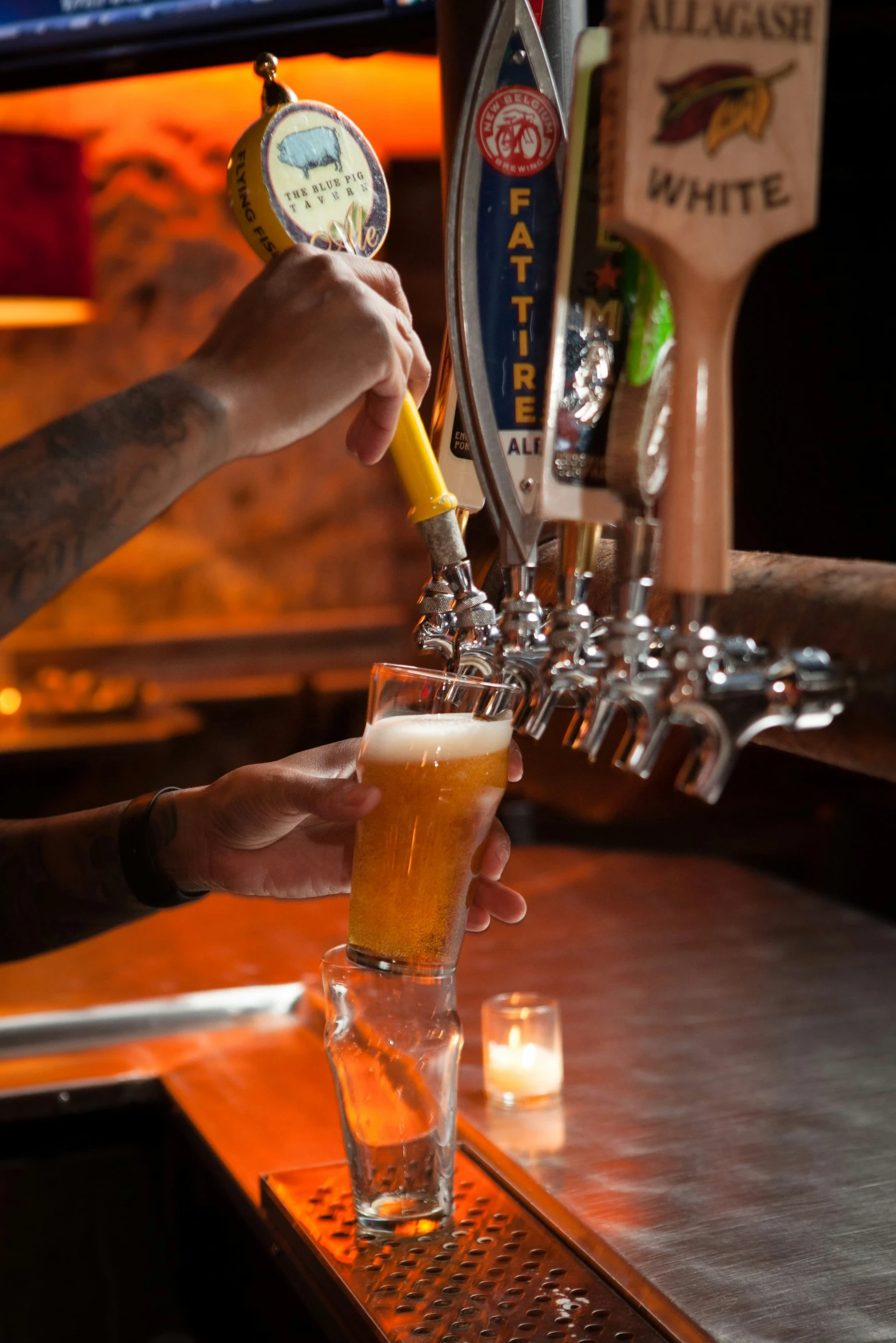 bartender pouring beer into a tall glass