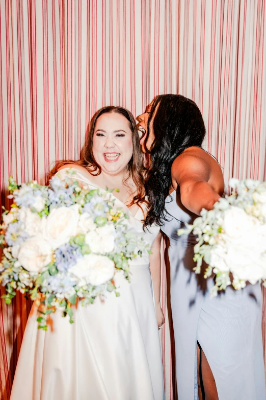 two women hugging in front of red striped wall