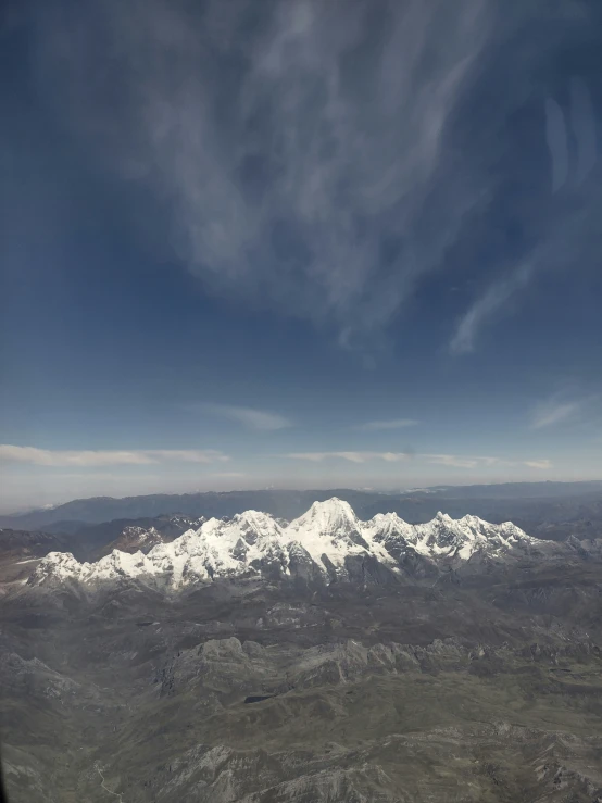 an airplane flying over a mountain range with snow capped mountains