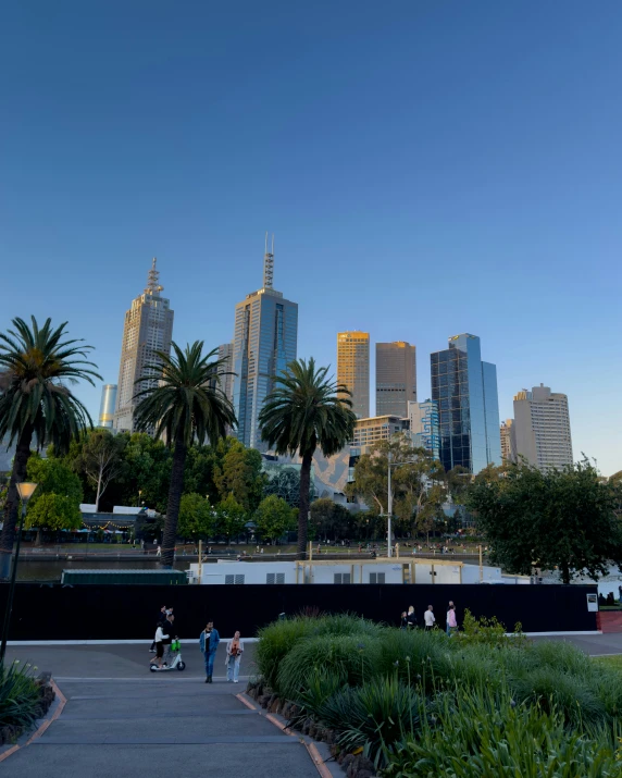 some people standing near trees near the water and buildings