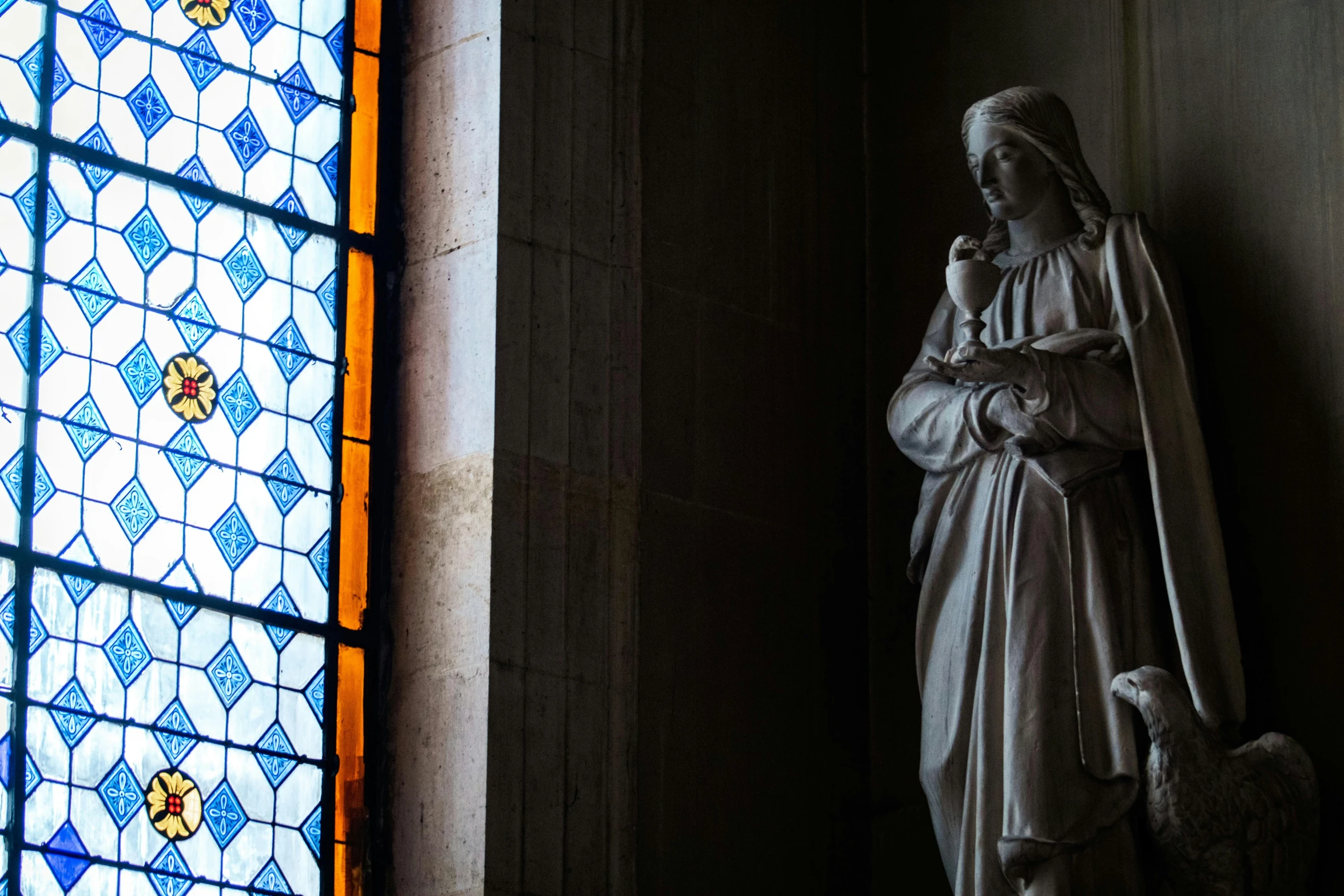 the statue is next to a stained glass window