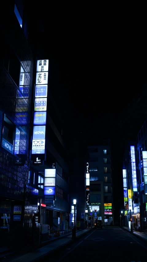a dark city street has many buildings lit up with advertits