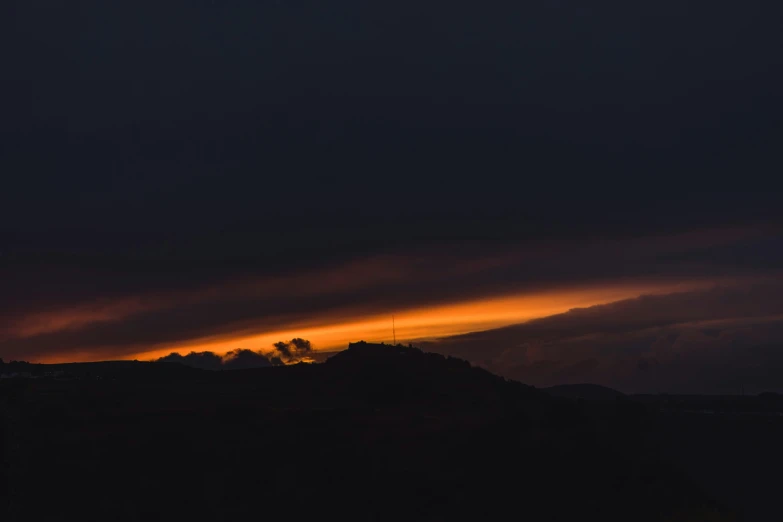 some hills are silhouetted against the evening sky