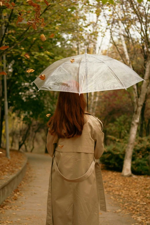 a woman walks down the path with a white umbrella