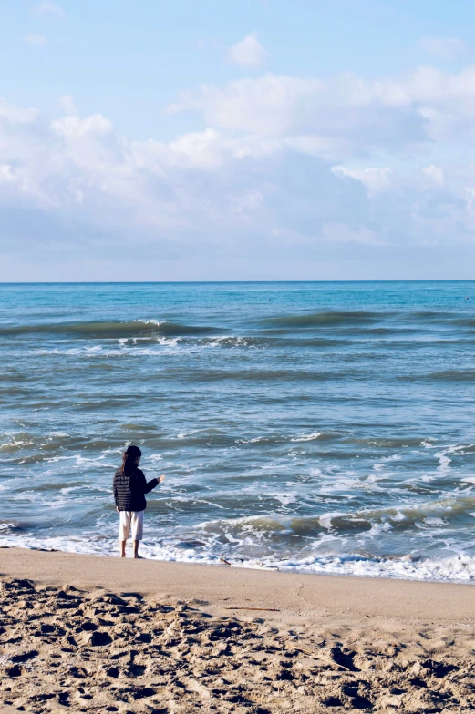 a person standing on top of a beach near the ocean