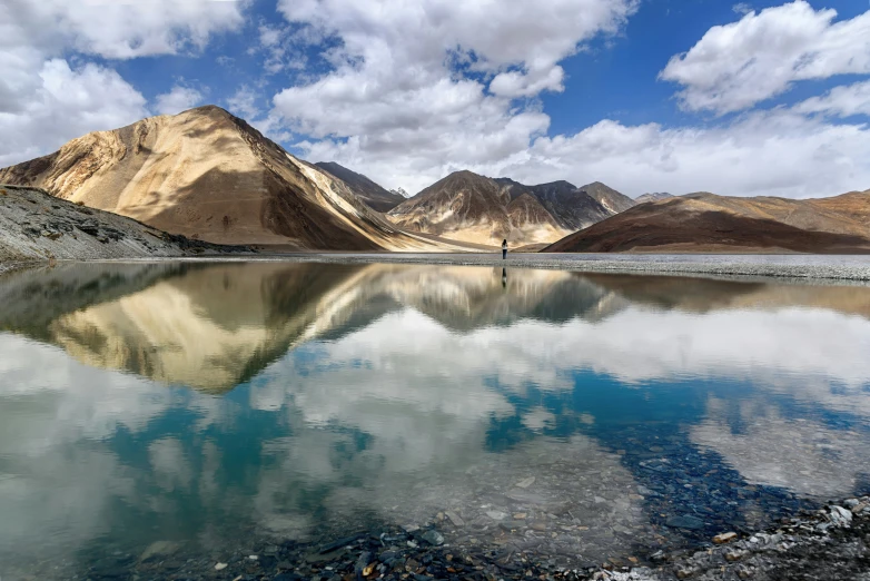 this is an image of a man on the edge of a lake in mountains