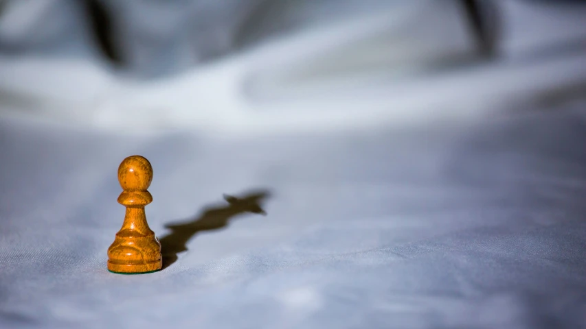 small wooden chess piece on a white cloth