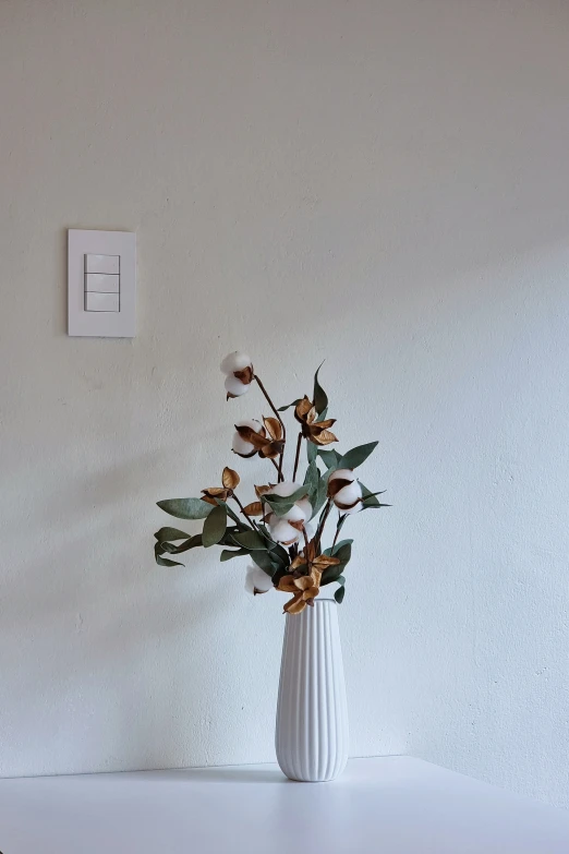 a white vase with flowers sitting on the table