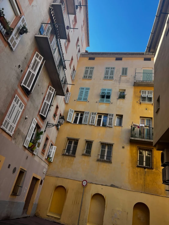 some yellow buildings have small white windows and shutters