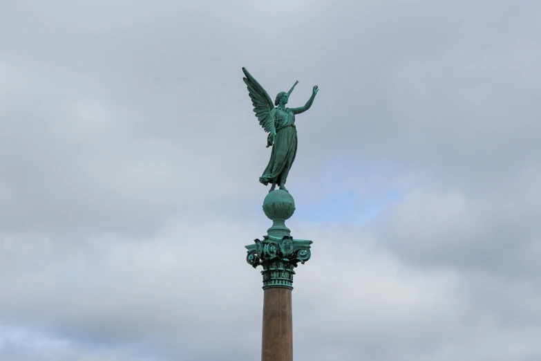 a statue is next to a column with a sky in the background