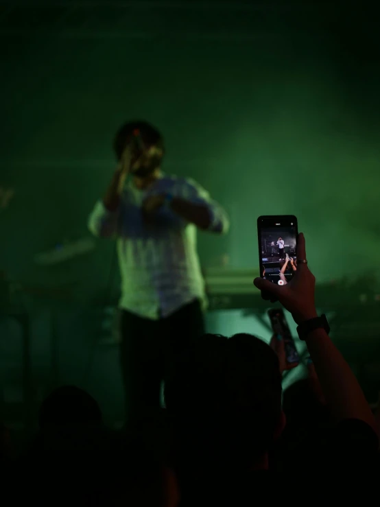 a man holding up a smart phone near a concert