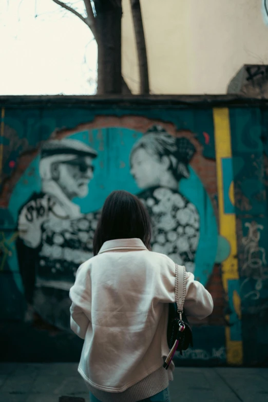 a woman in a white jacket is looking at graffiti