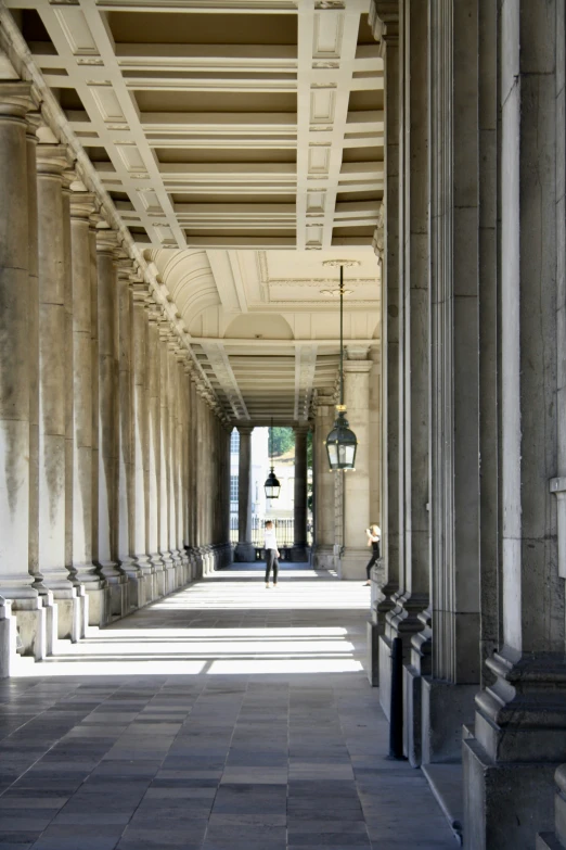 long empty corridor with white columns and two lamps on the ceiling