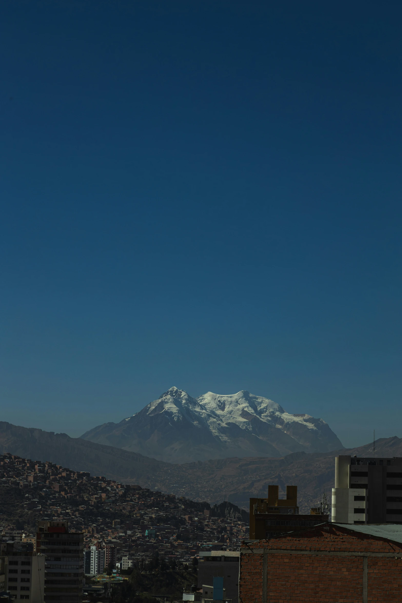 a city with mountains in the distance under a blue sky