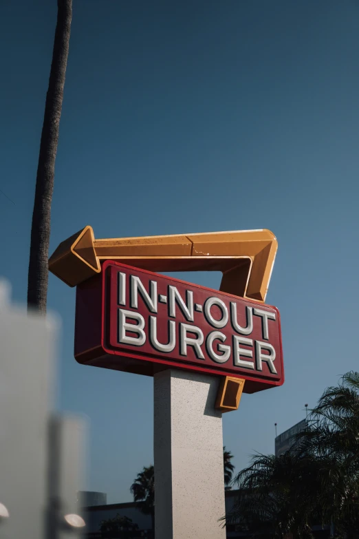 a big sign for an inn out burger in front of the palm tree