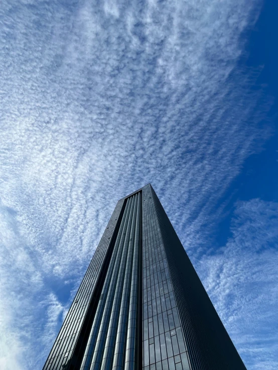 the corner of a building, with tall windows and clouds