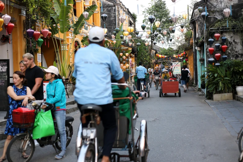 people riding bikes down the street by shops