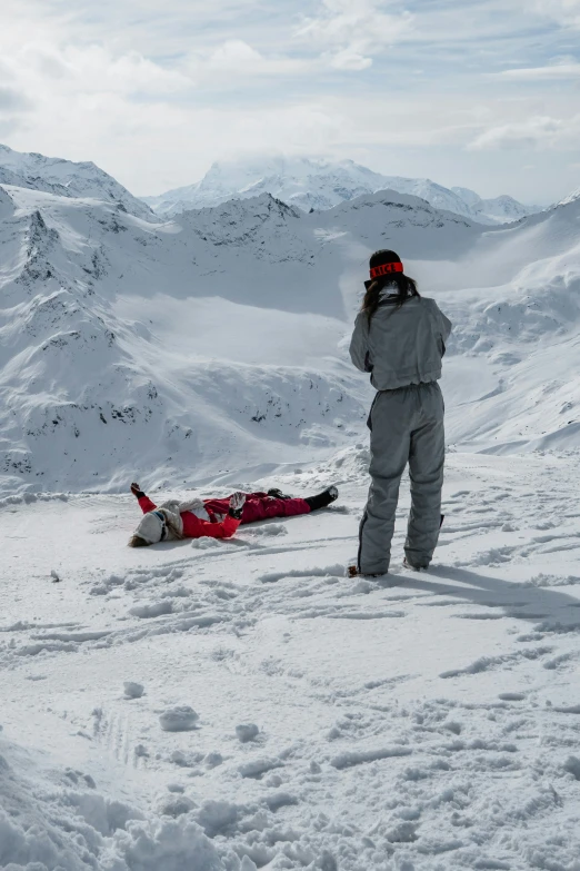 a person standing over a person lying on the snow