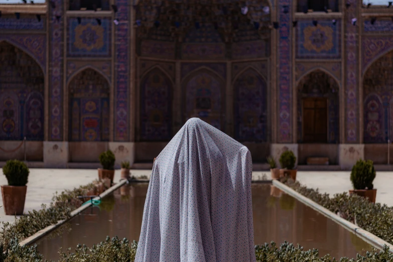 a covered person standing in front of an ornate building