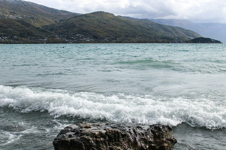 the wave is breaking on the shore, as a city sits in the background