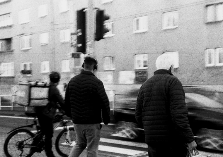 three people crossing the street and moving cars