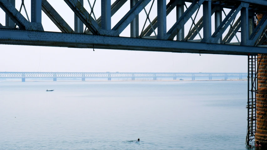 a person swimming under an overpass over a body of water