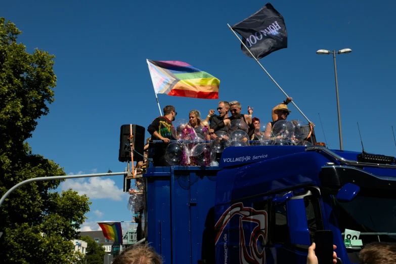 people on top of a blue bus in front of trees