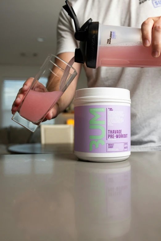 a man pouring liquid from a plastic blender onto a jar of dye