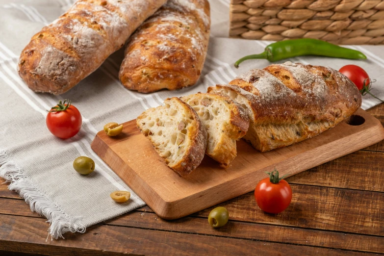 bread, tomatoes and vegetables sit on a wooden board